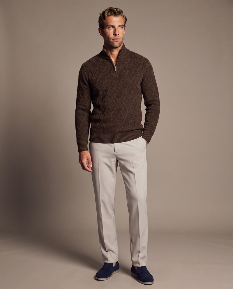 SATRI & CO. model wearing a chocolate-brown diamond cable-knit quarter zip, stone trousers and navy suede loafers
